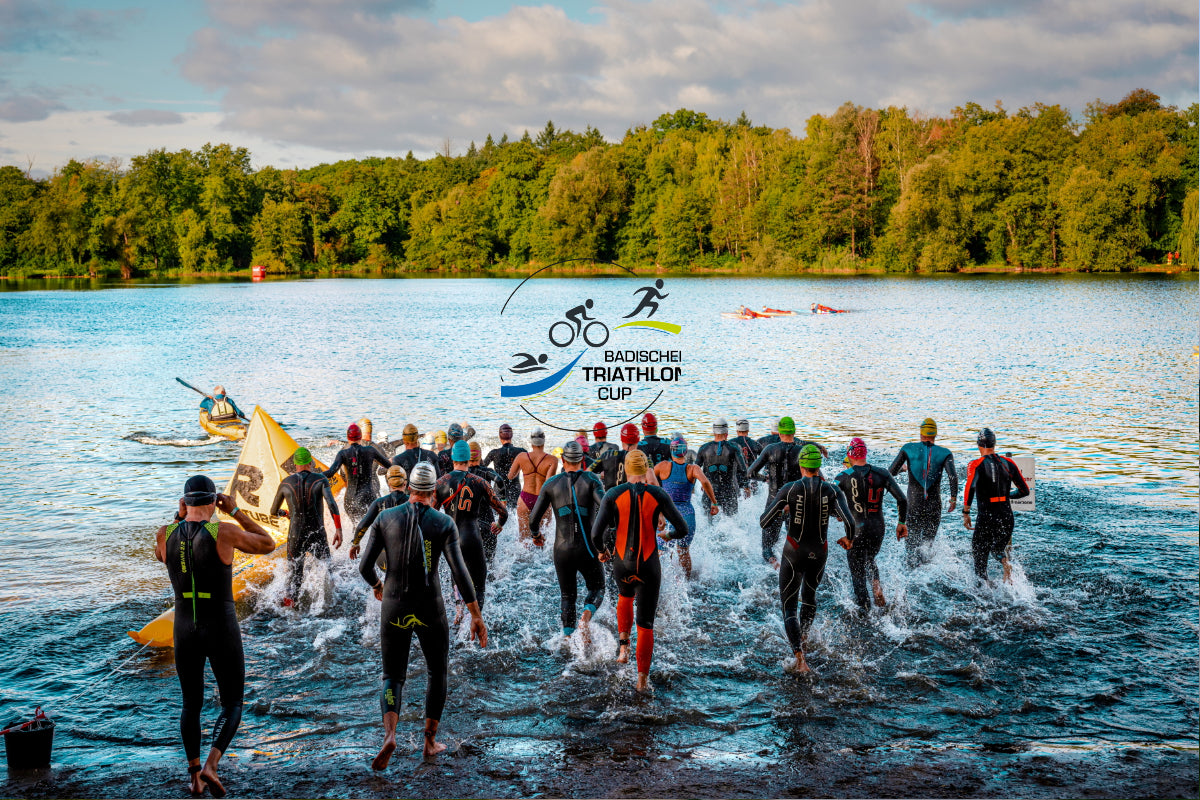 Mehrere Triathleten laufen im Neoprenanzug in einen See, Ansicht von hinten
