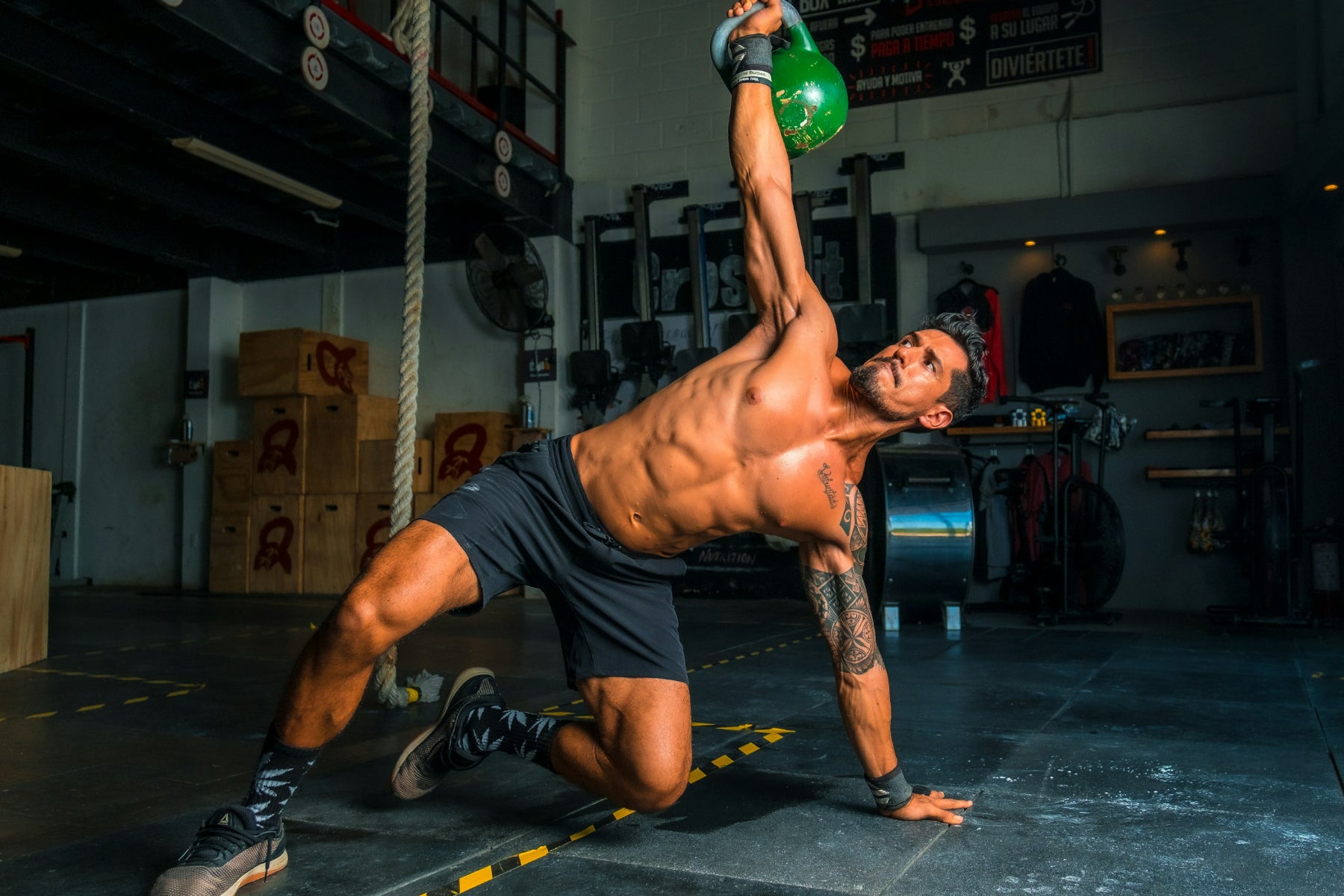 Mann im Fitnessstudio hebt eine Hantel einarmig nach oben