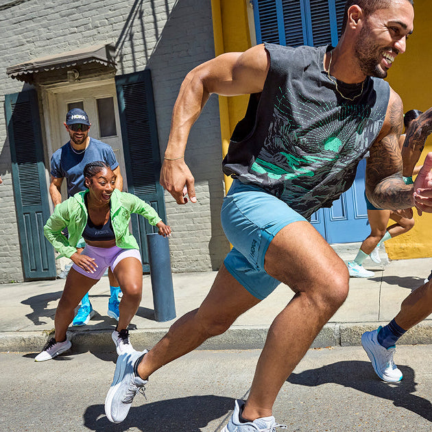Eine Gruppe von Läuferinnen und Läufern starten euphorisch ihren Lauf auf einer Straße